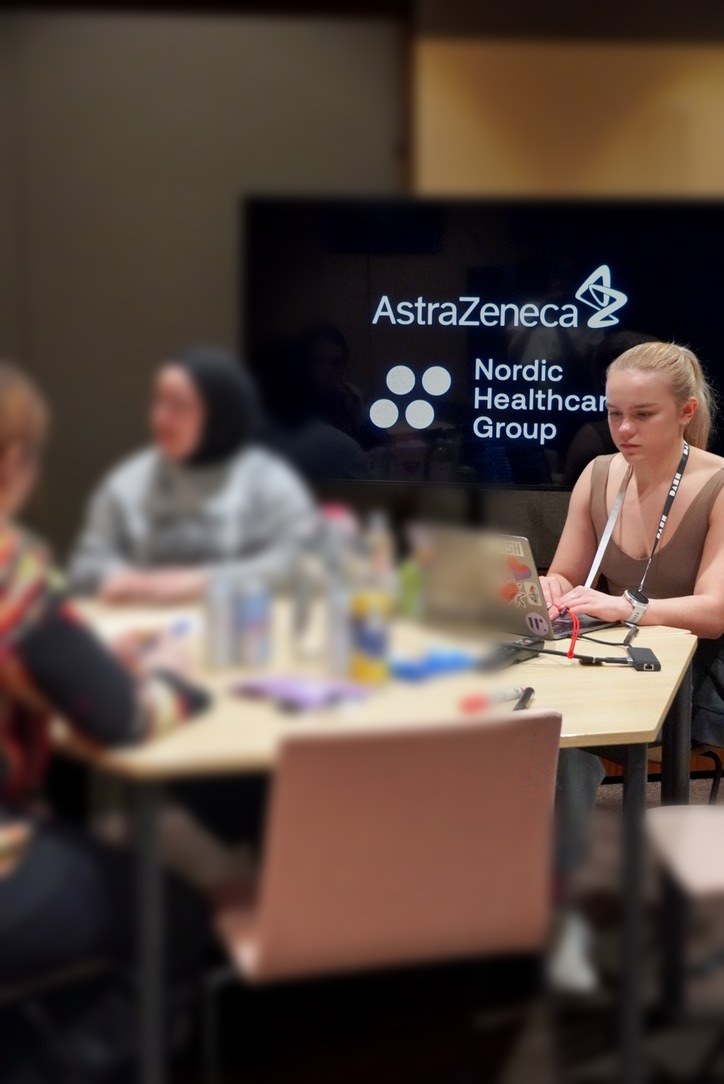 A sprint team working at a table in front of the AstraZeneca and Nordic Healthcare Group screen.